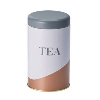 Rund stilfuld tedåse i primært hvid, bronze i bunden og gråt låg med ordet "Tea" i centrum